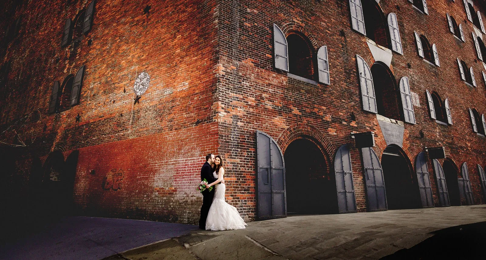 Couple posing for a portrait in front of a brick building